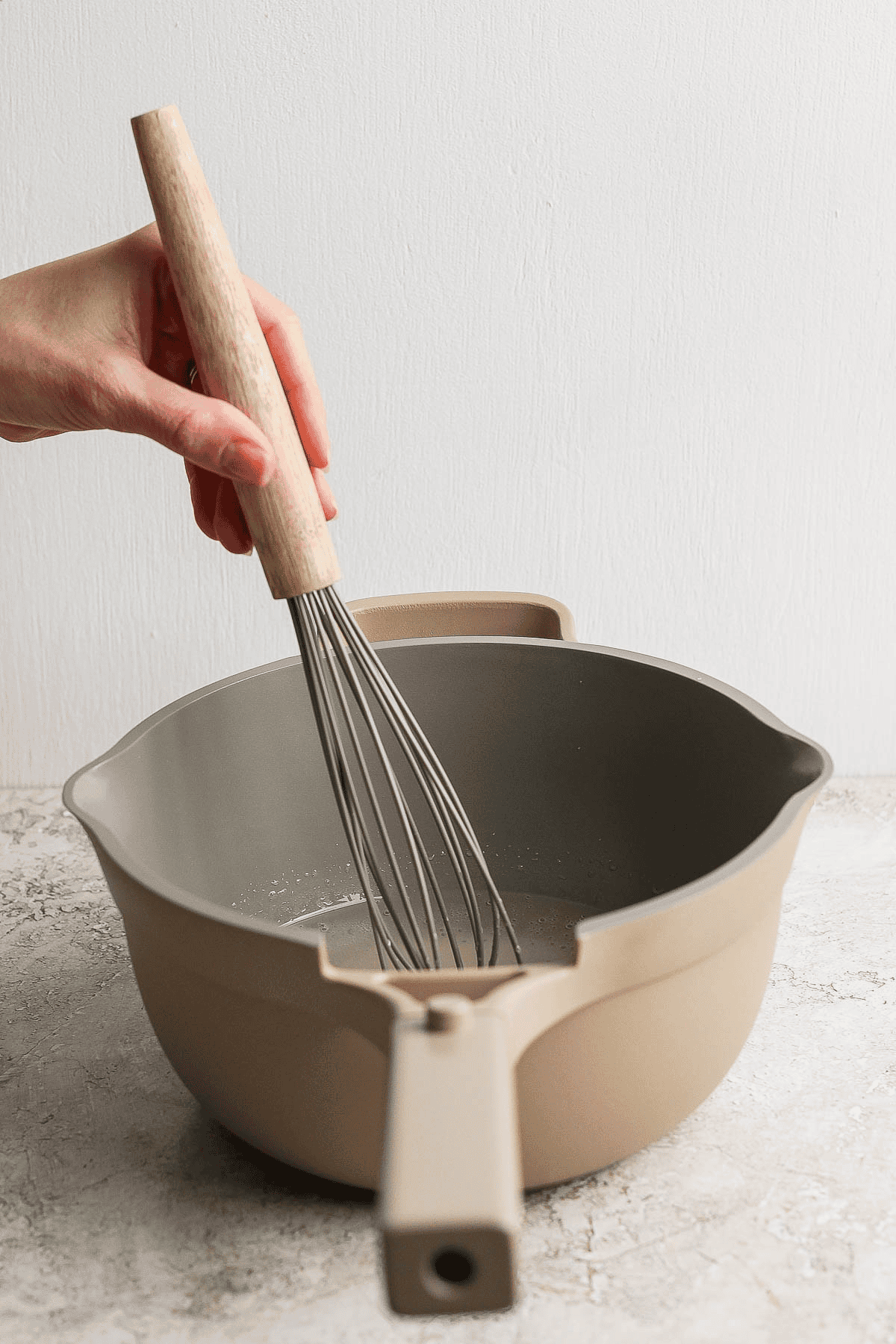 A whisk mixing the champagne mixture for champagne jello shots in a sauce pan.