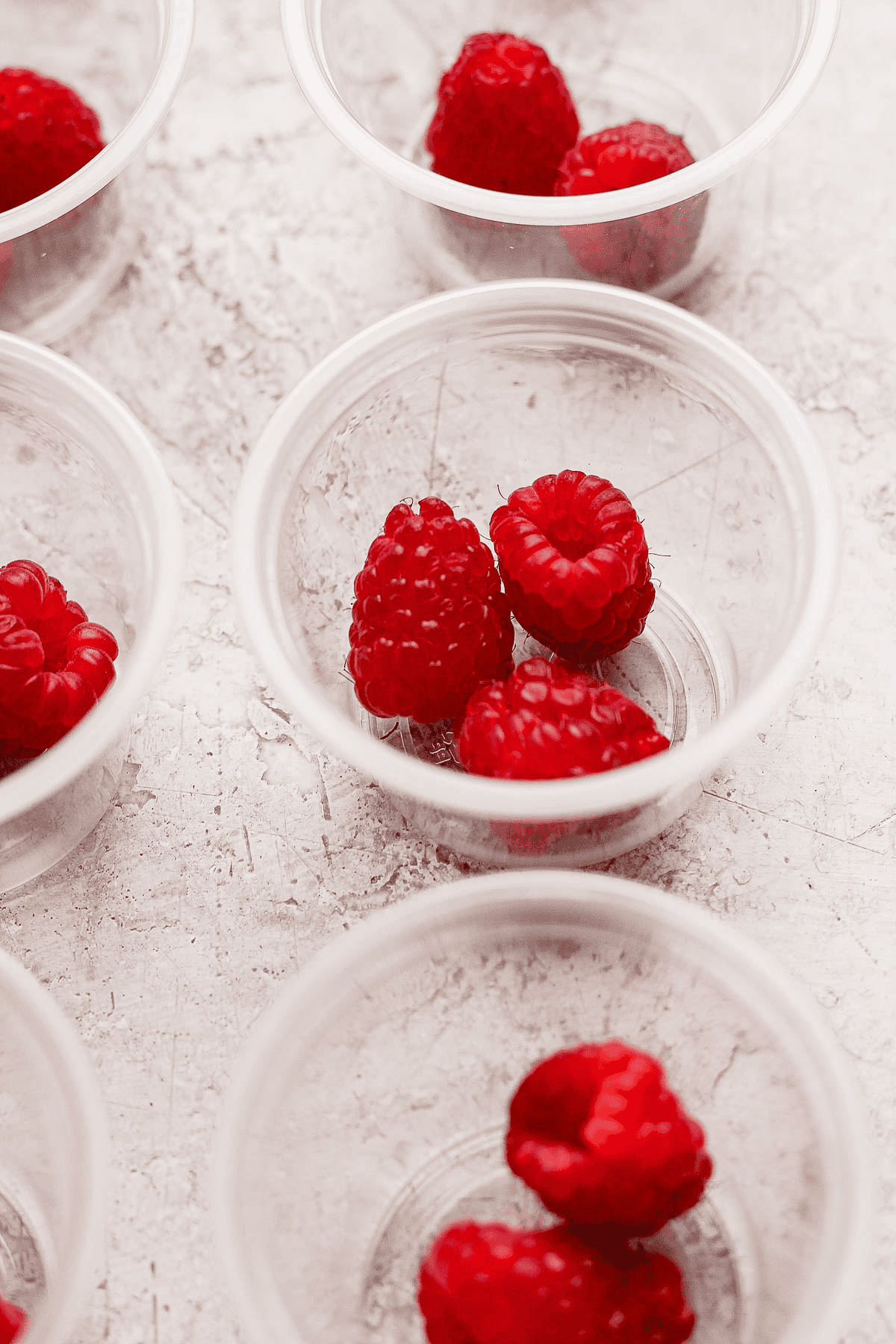 Fresh raspberries in a few plastic cups.