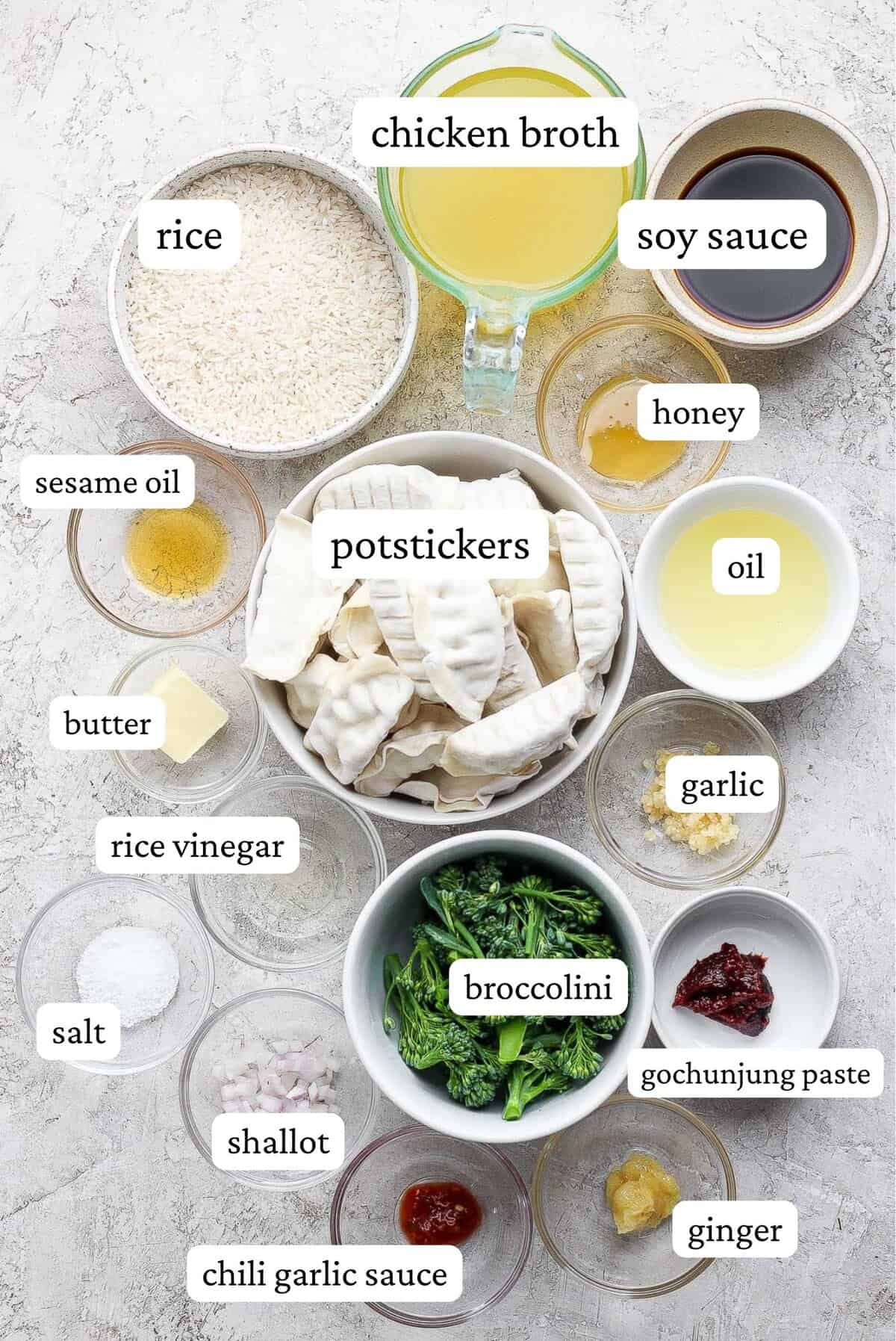 Ingredients for dumpling bake including rice, chicken broth, soy sauce, honey, sesame oil, potstickers, butter, oil, garlic, rice vinegar, broccolini, salt, shallots, gochunjung paste, ginger, and chili garlic sauce.