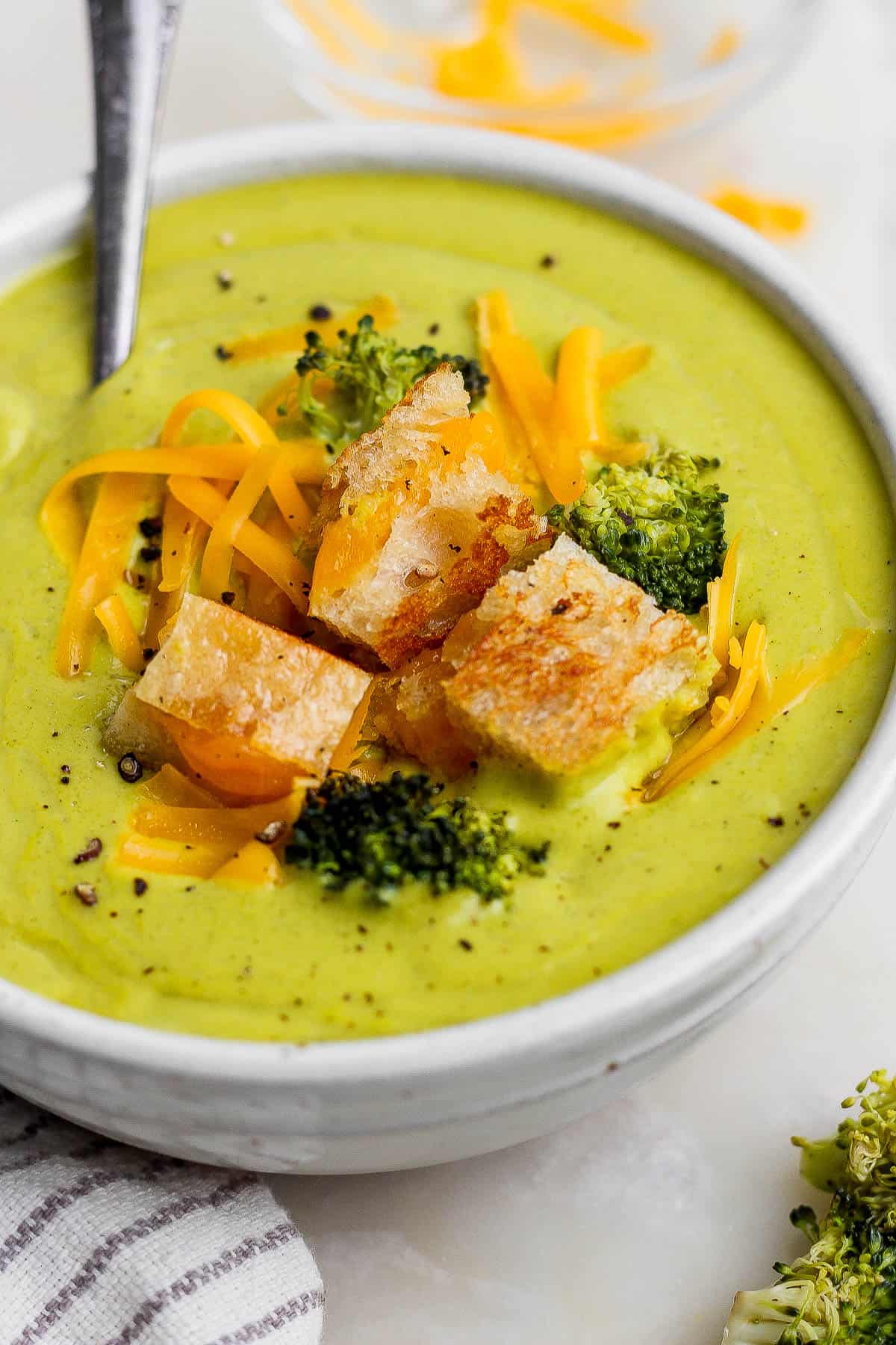 Sheet pan soup in a bowl topped with roasted veggies, shredded cheese, and grilled cheese croutons.