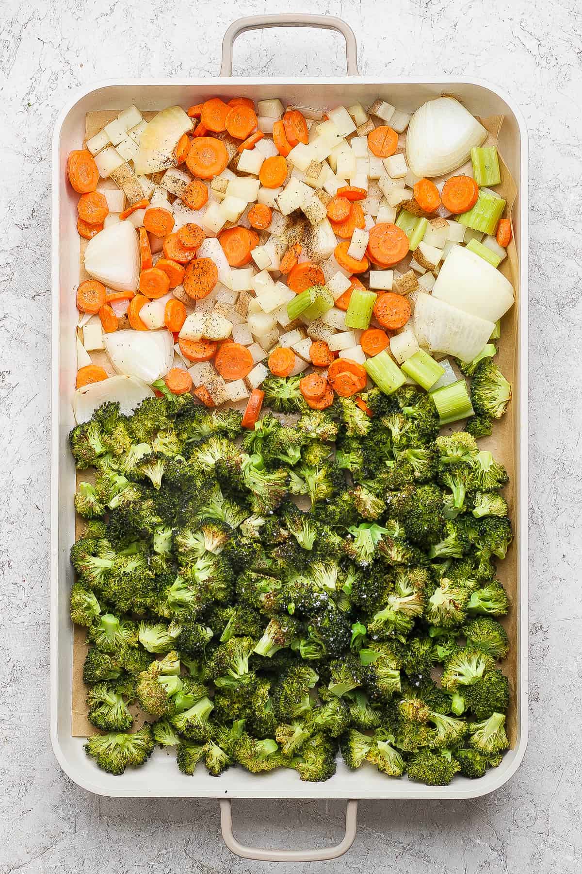 Broccoli, onions, carrots, and celery on a roasting pan to make sheet pan soup.