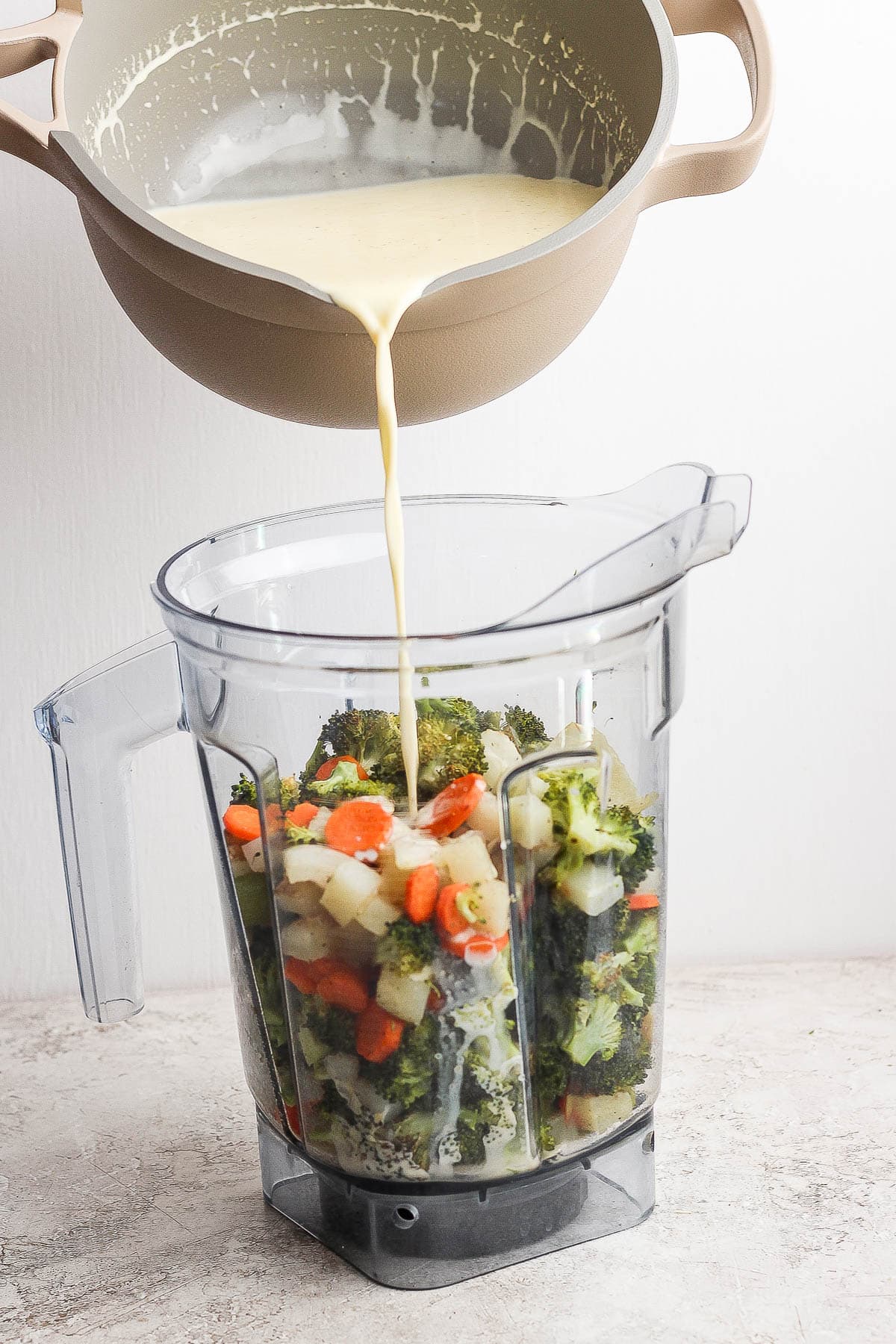 Creamy roux being poured into blender along with the roasted veggies to make sheet pan soup.