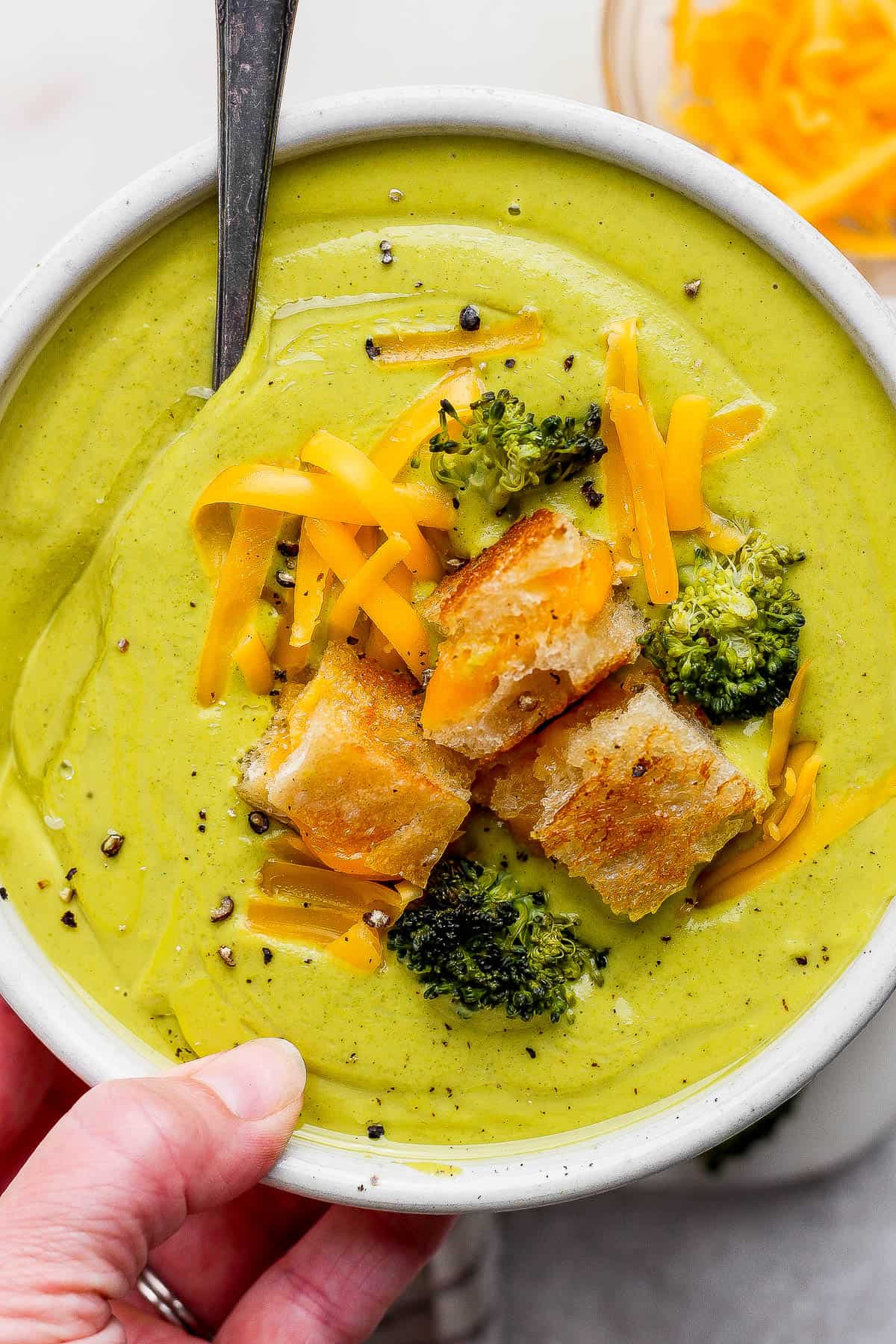 A bowl of sheet pan soup with grilled cheese croutons on top and a spoon sticking out the side.
