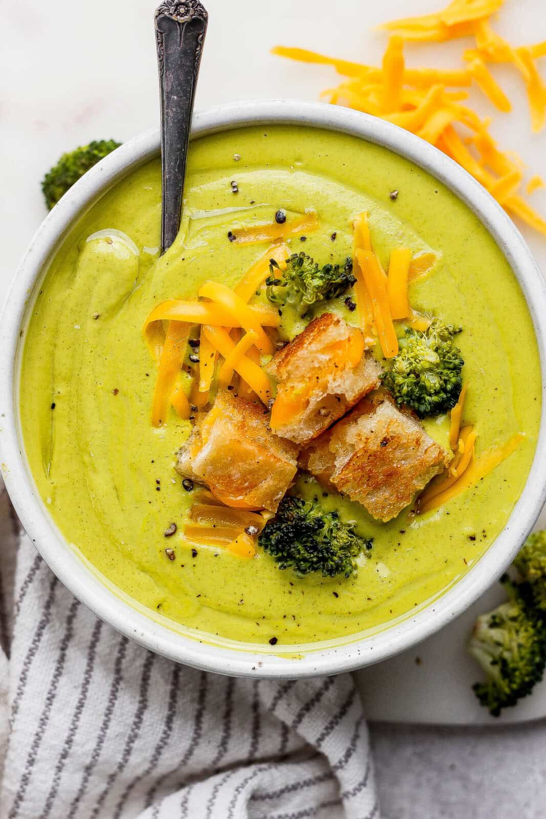 Sheet pan soup poured into a bowl topped with roasted veggies, shredded cheese, and grilled cheese croutons.