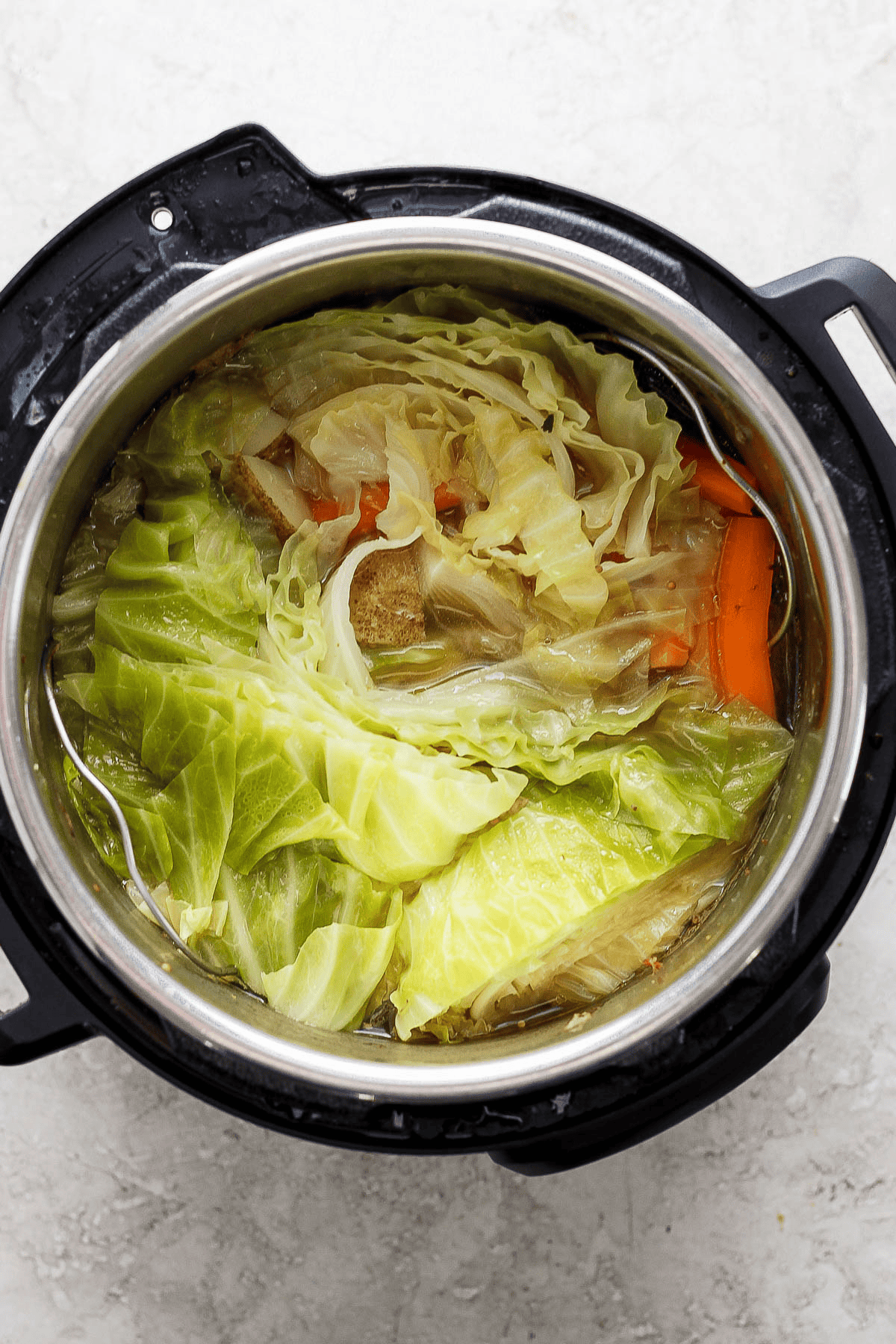 Fully cooked cabbage, potatoes, carrots, and onion in an Instant Pot.