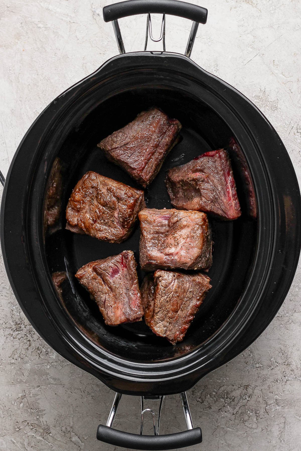 Six braised short ribs in a crock pot to make short rib tacos.