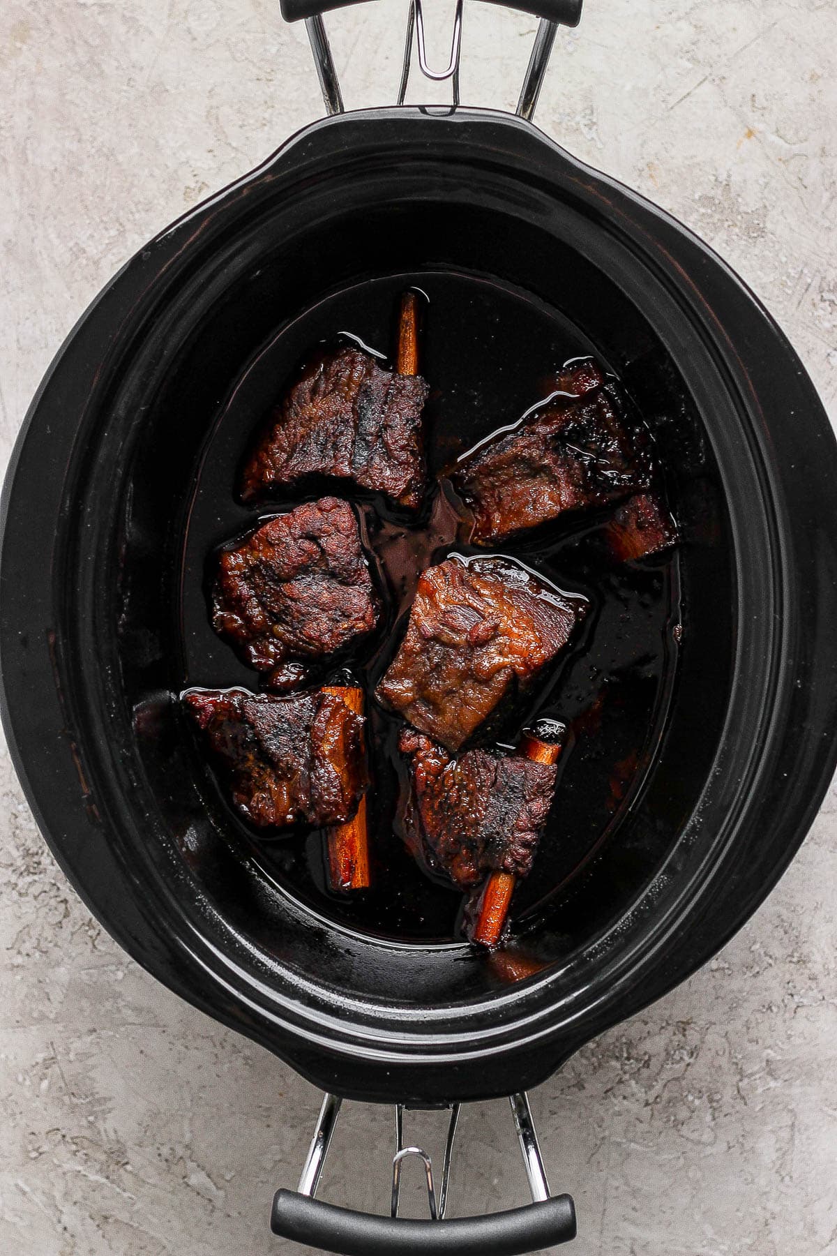 Six short ribs in a crock pot with korean BBQ sauce to make short rib tacos.