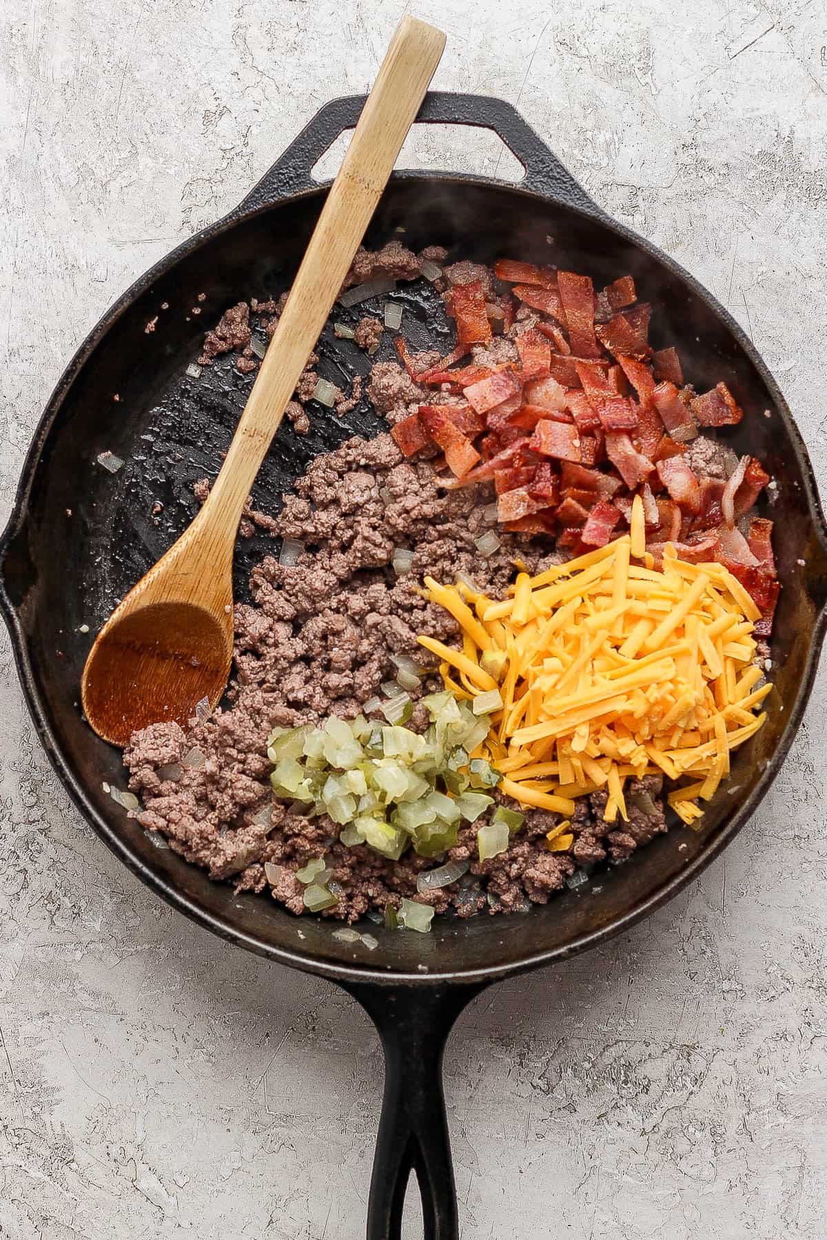 Cooked meat mixture with added bacon, pickles, and cheddar cheese to make cheeseburger egg roll filling.