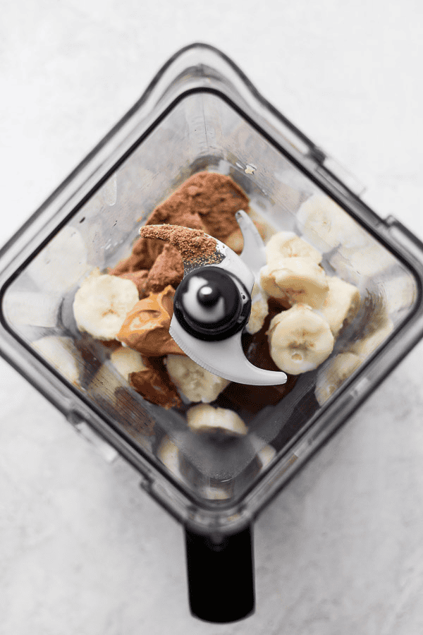 Ingredients for a coffee smoothie in a blender before being mixed.