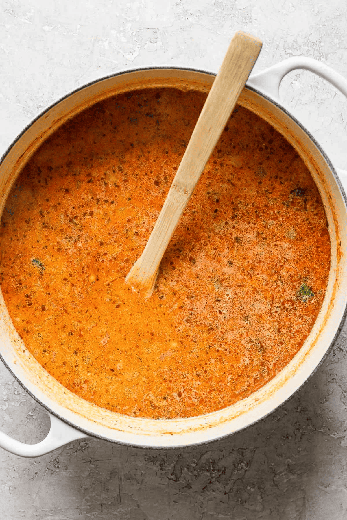 Creamy taco soup in a large white pot with a wooden spoon sticking out the side.