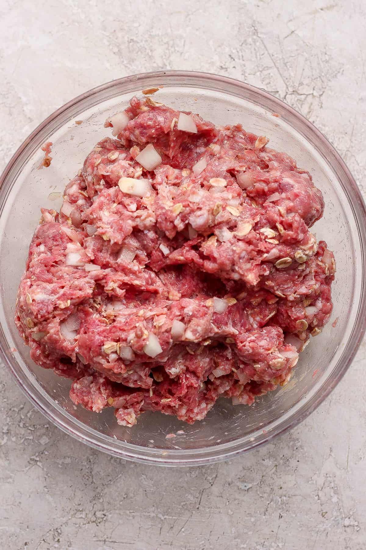Ingredients for a healthy meatloaf fully mixed together in a glass bowl.