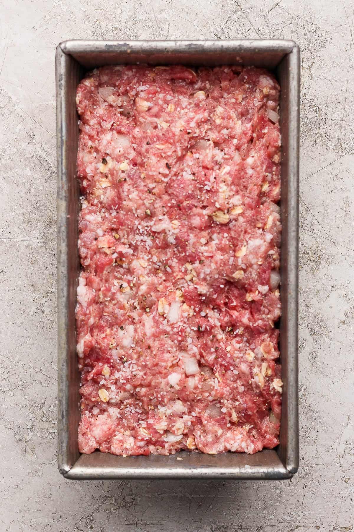 A healthy meatloaf in a bread pan before baking.