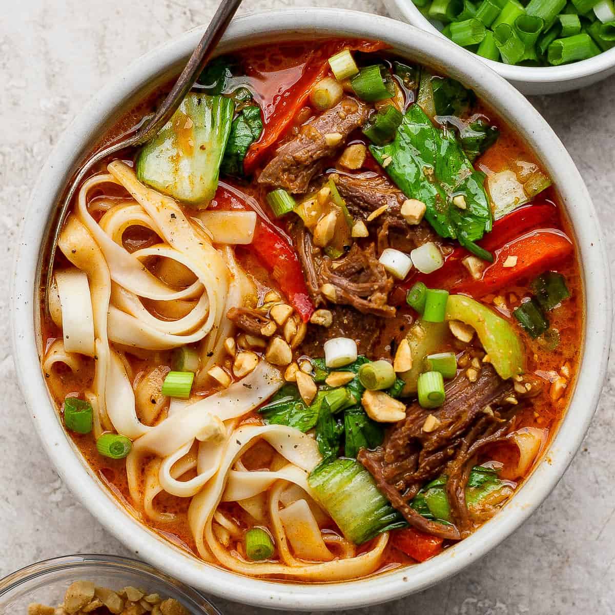 Bowl of beef short rib soup with a spoon sticking out the side.