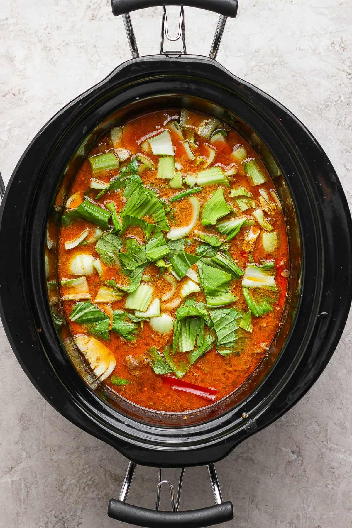 Chopped bok choy added to slow cooker to make beef short rib soup.