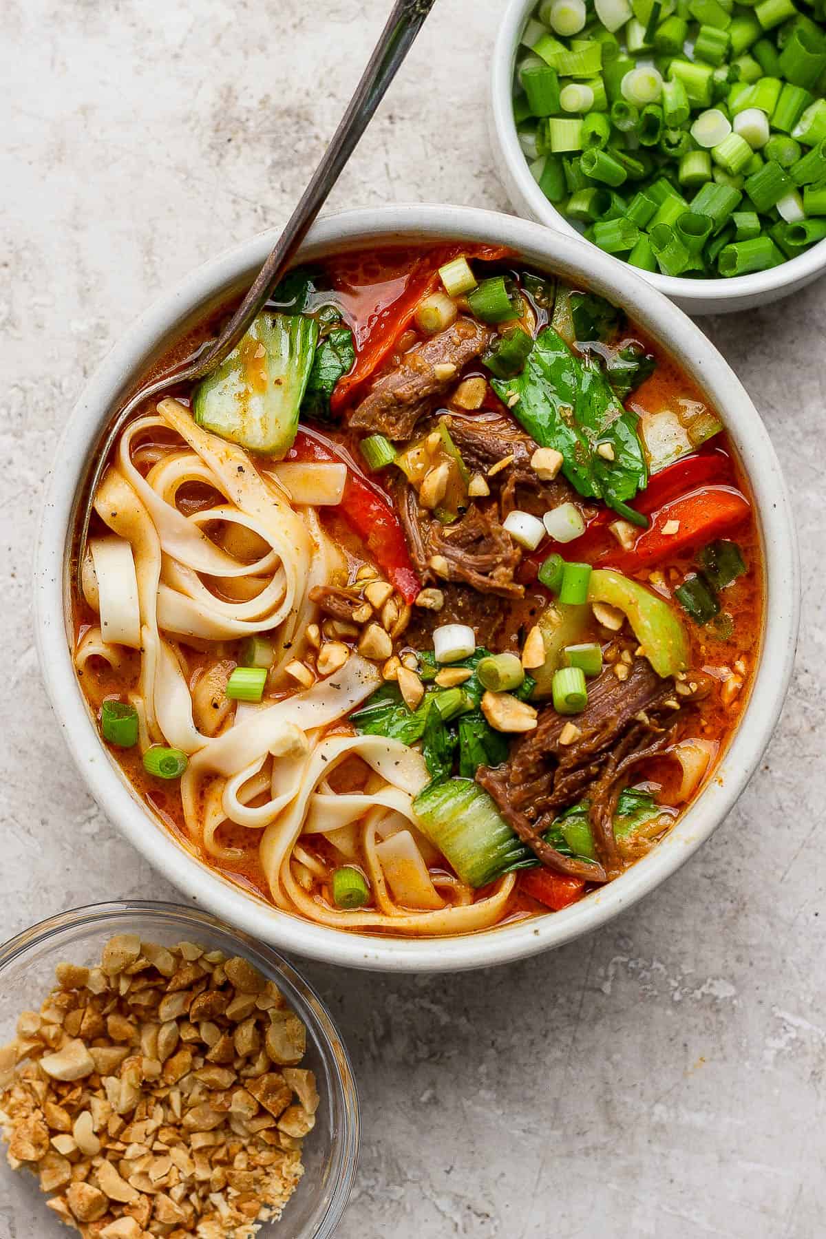 A bowl of beef short rib soup topped with crushed peanuts and sliced green onion.