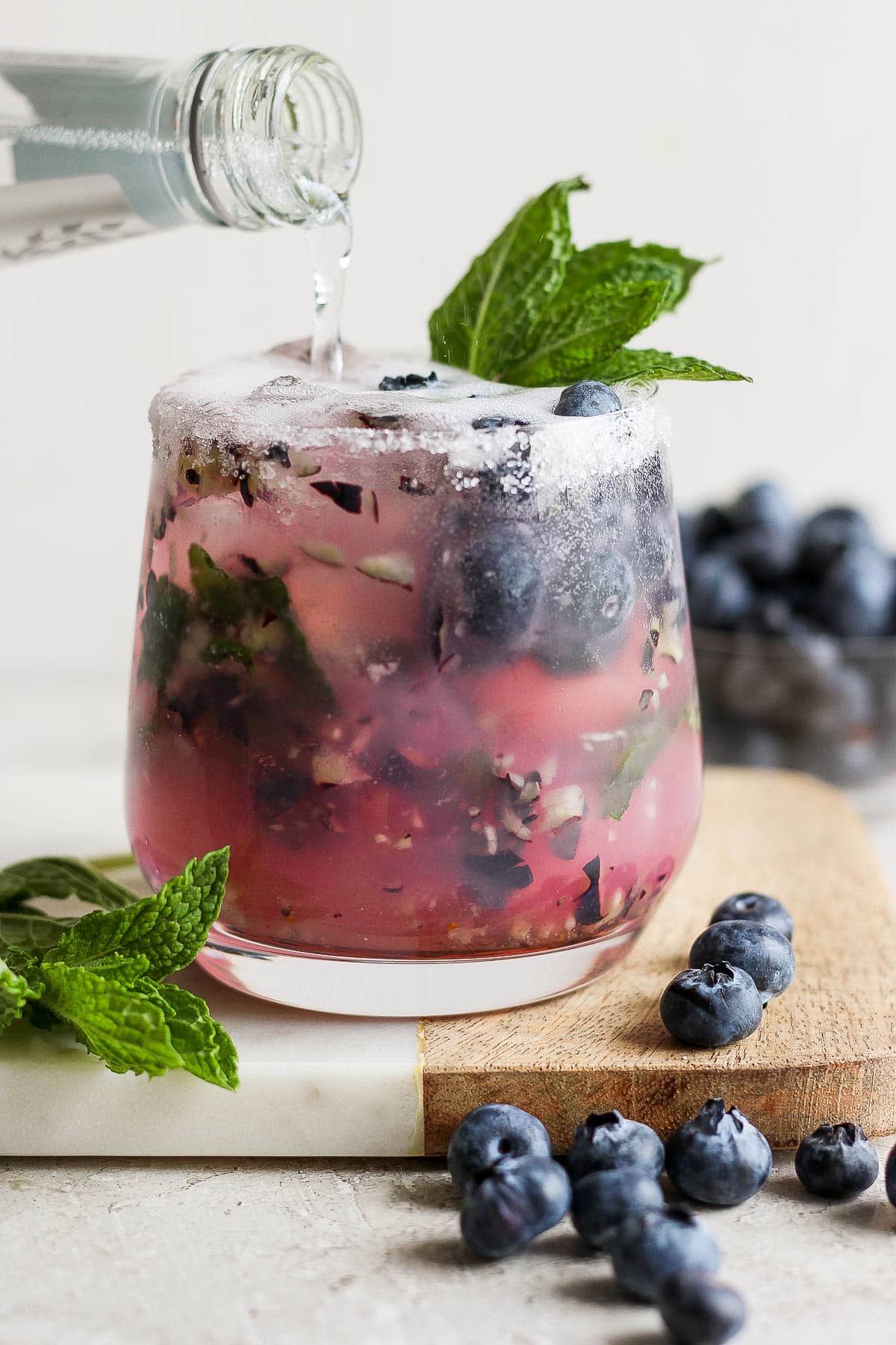 A blueberry mojito being topped with tonic water.