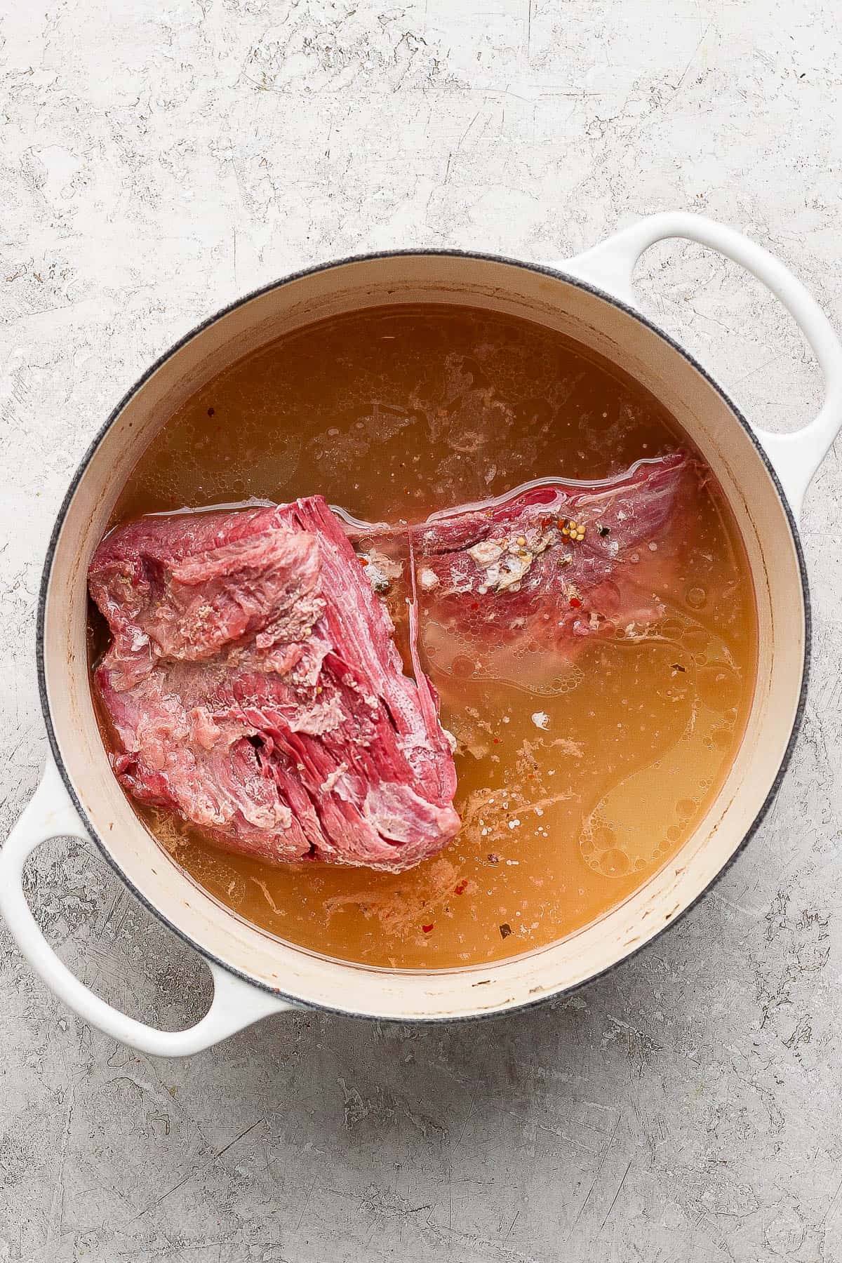 A corned beef brisket and seasoning packet cooked in water after 3 hours.