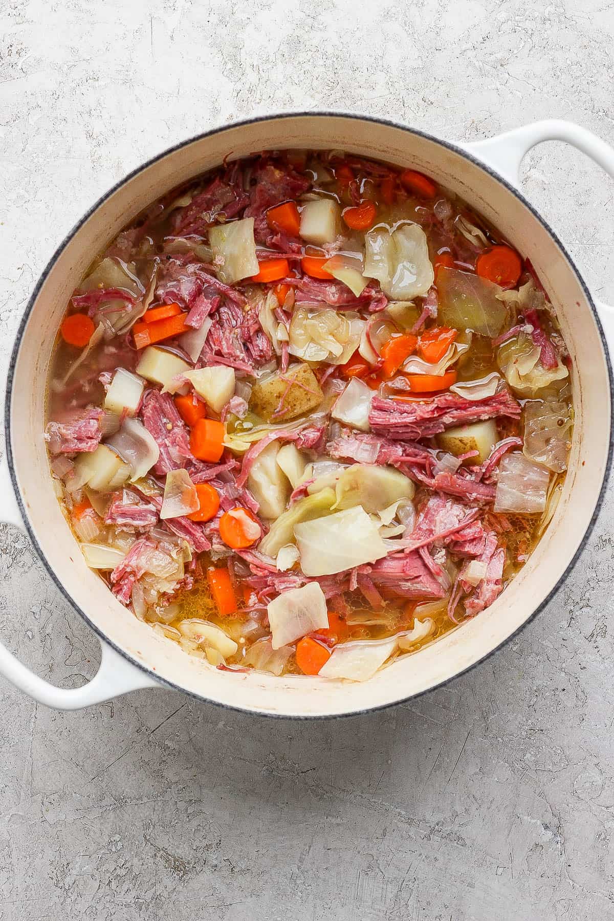 Corned beef and cabbage soup in a white dutch oven after simmering.