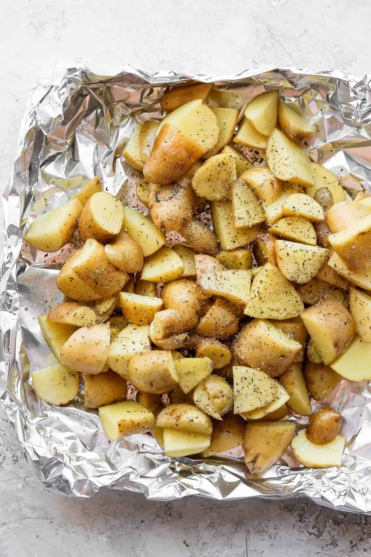 Seasoned potatoes in a foil pan before going on the smoker.