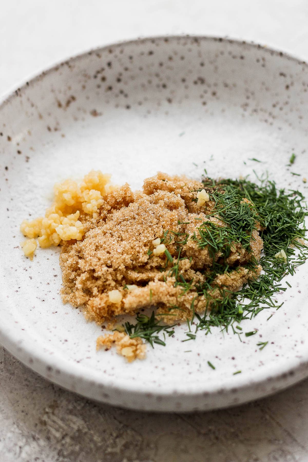 Ingredients for a smoked salmon dry brine in a shallow bowl before being mixed.