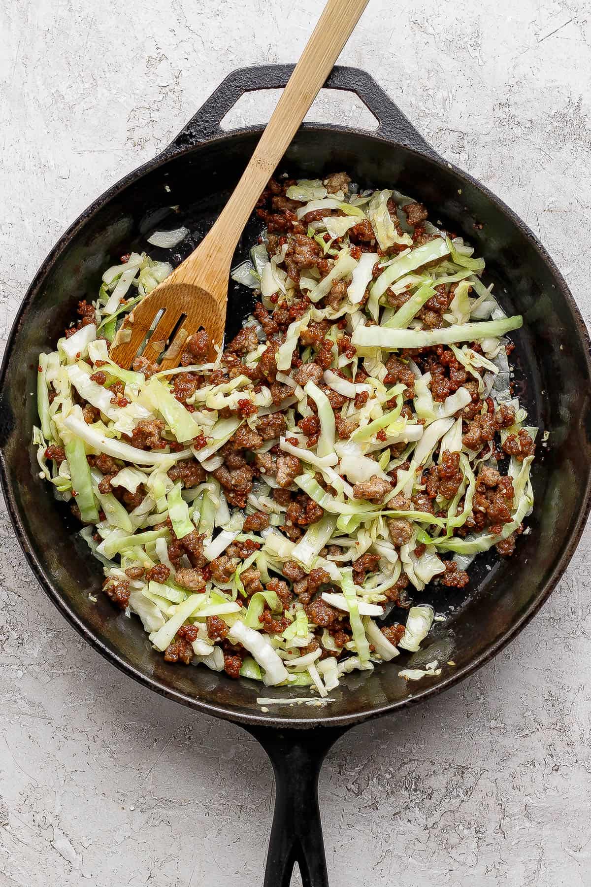 Sautéed cabbage and garlic in a cast iron skillet with crispy pork.