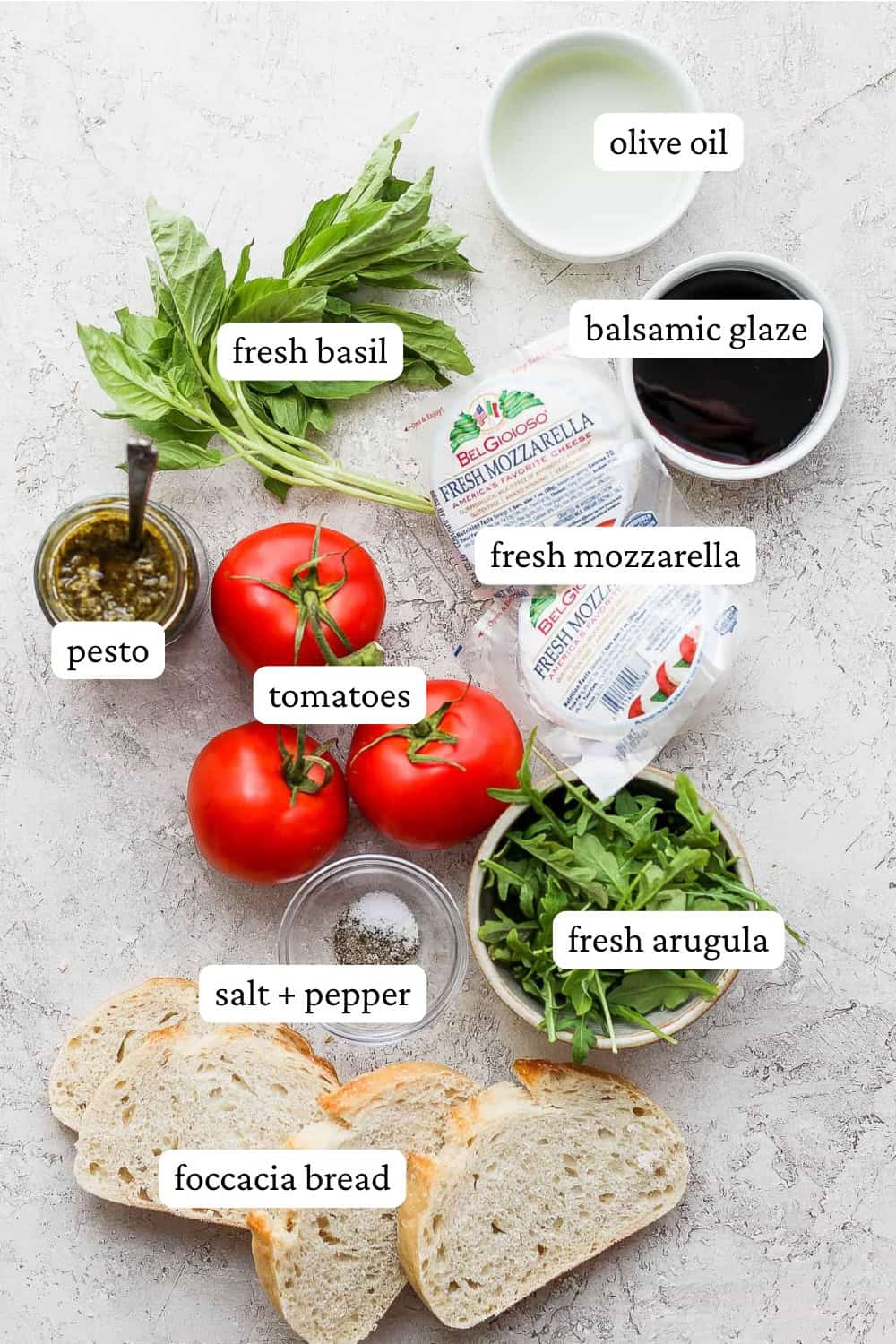 All of the ingredients for caprese sandwiches laid out on the counter with labels.