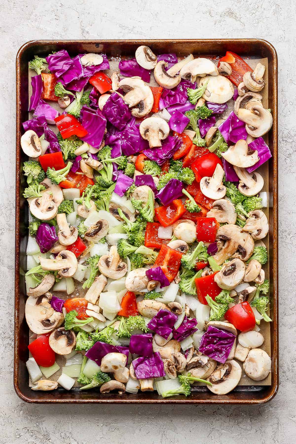 A large baking sheet full of chopped and sliced vegetables to roast in the oven.