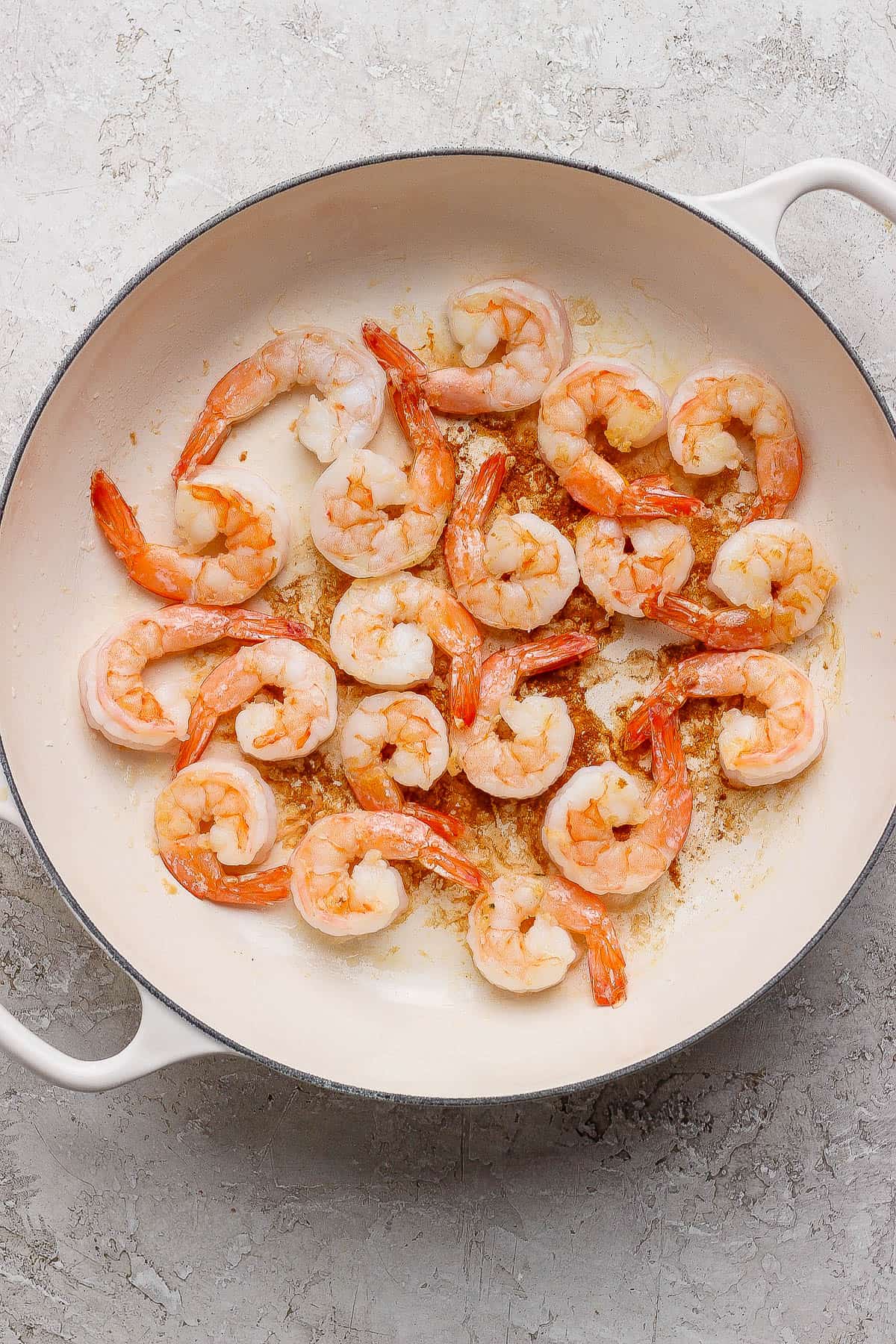 Large shrimp pan-frying in a braising pan.
