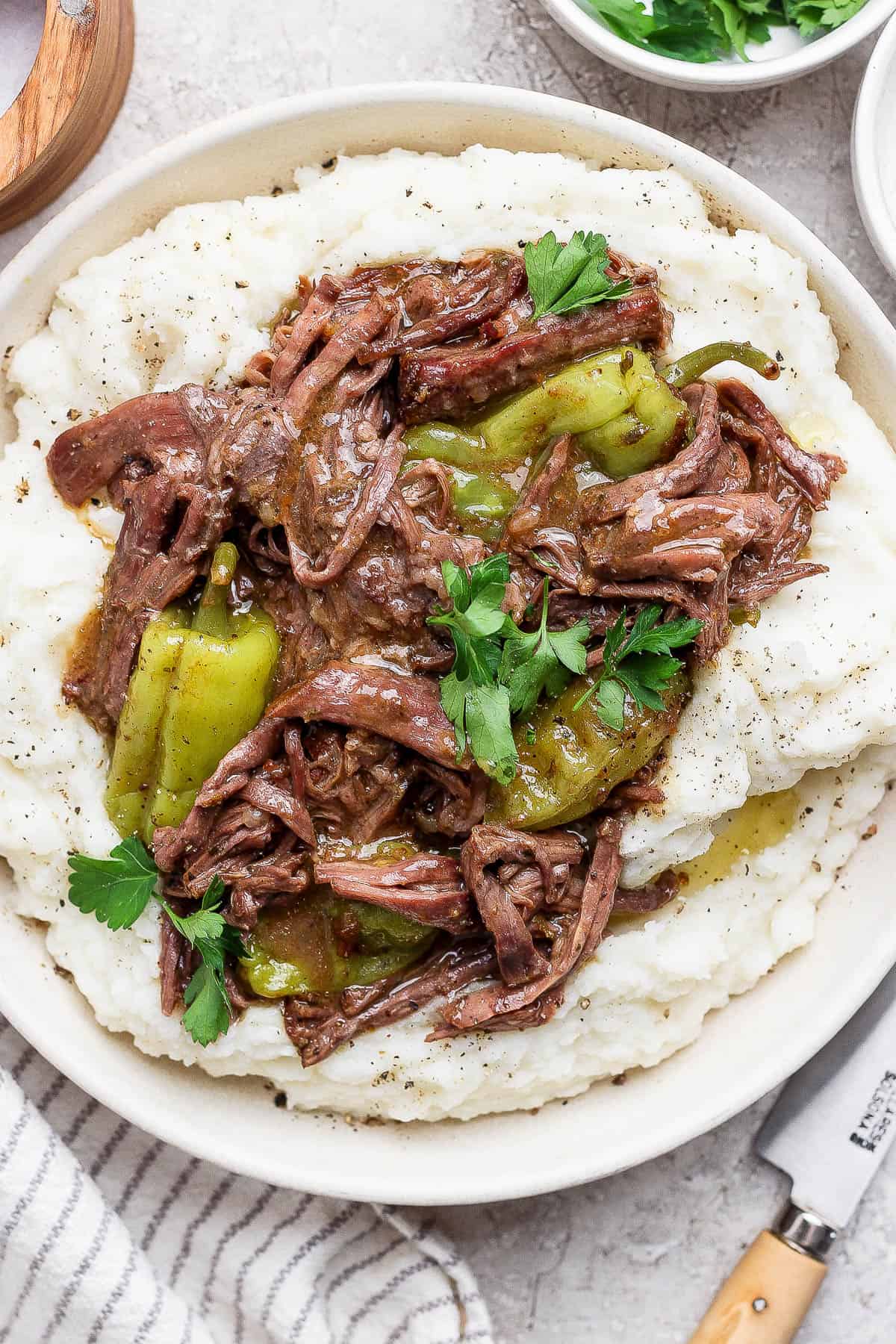 Dutch oven mississippi pot roast served over mashed potatoes on a plate.