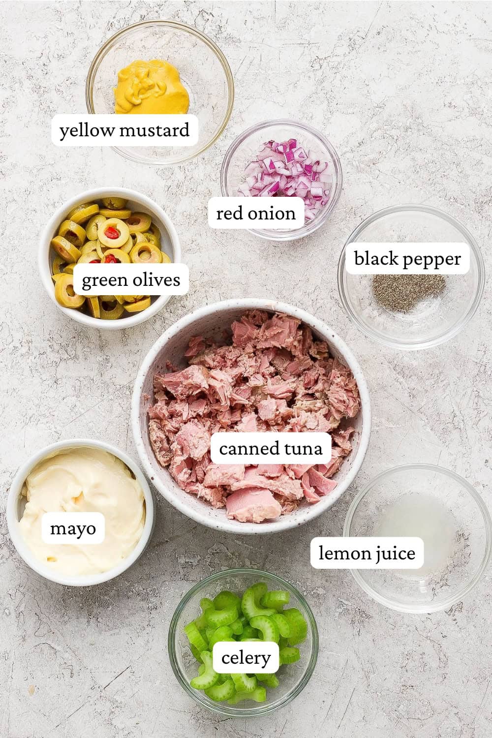Ingredients for a healthy tuna salad with olives in separate bowls with labels.