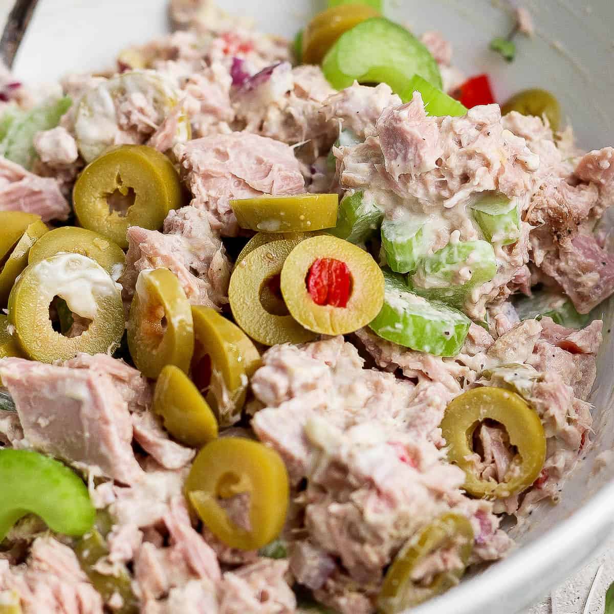 A fully mixed healthy tuna salad with olives in a bowl.