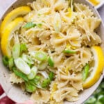 Lemon pasta salad in a bowl with slices of lemon and green onions.