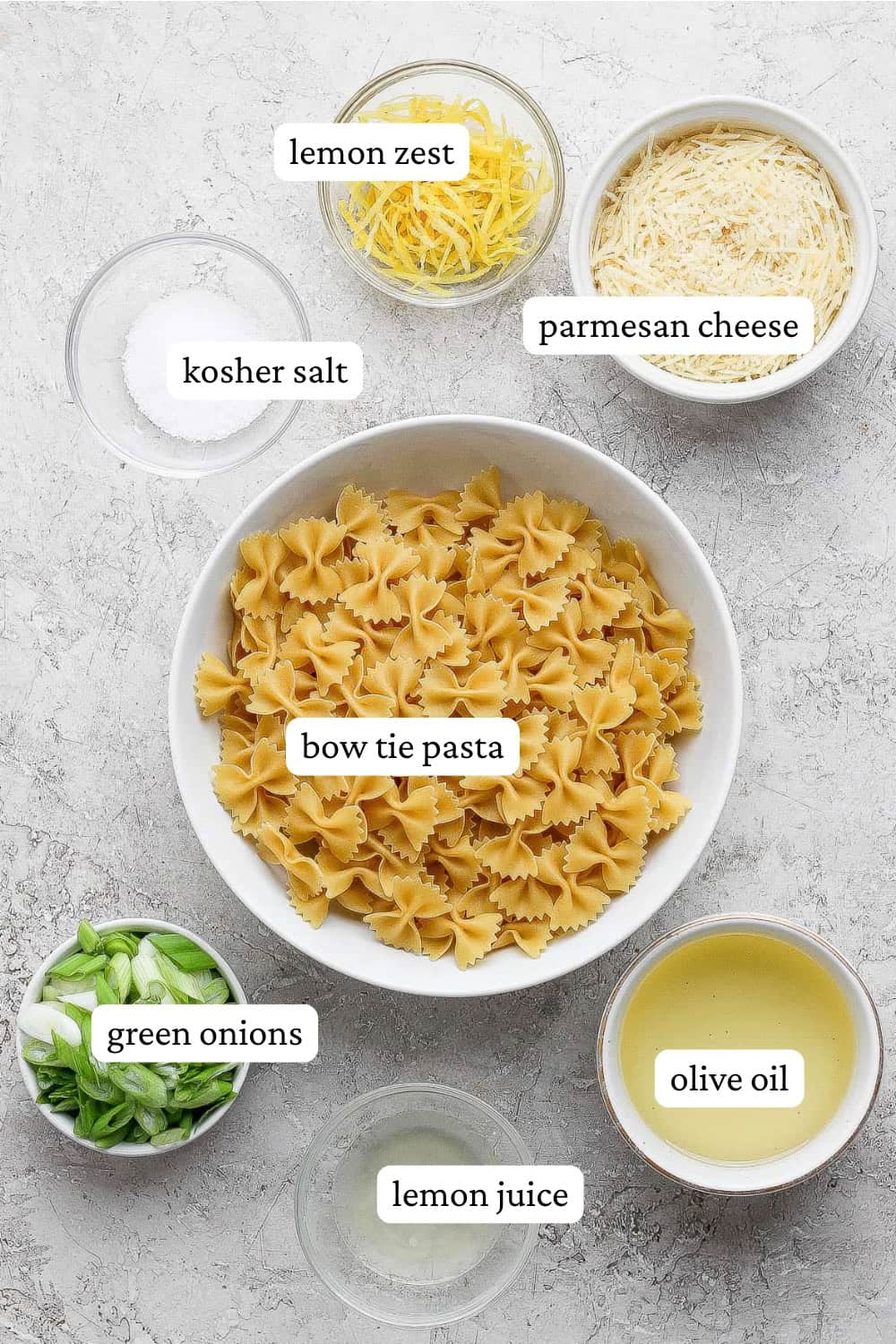 Ingredients for lemon pasta salad in separate bowls with labels.