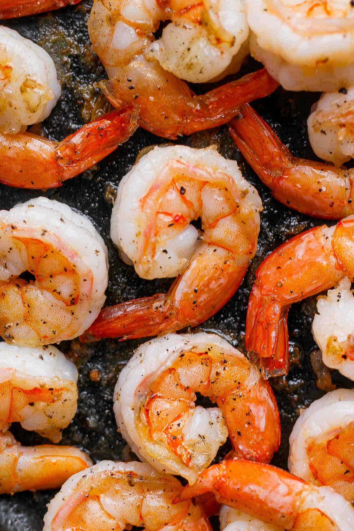 Fully cooked pan fried shrimp in a cast iron skillet.