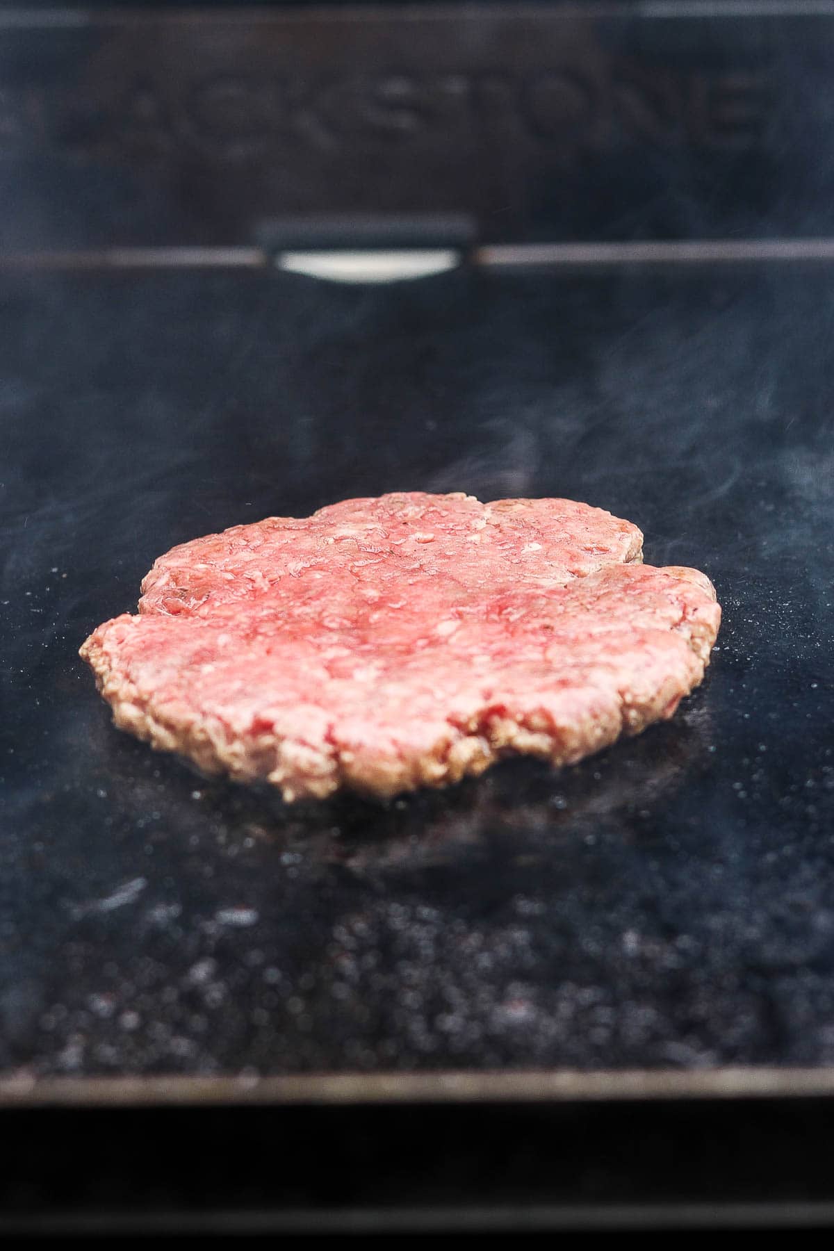 A smashed Blackstone smash burger patty cooking on the griddle.