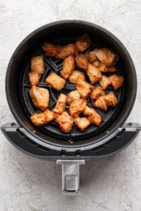 Chicken for bang bang chicken bowls cooking in an air fryer basket.