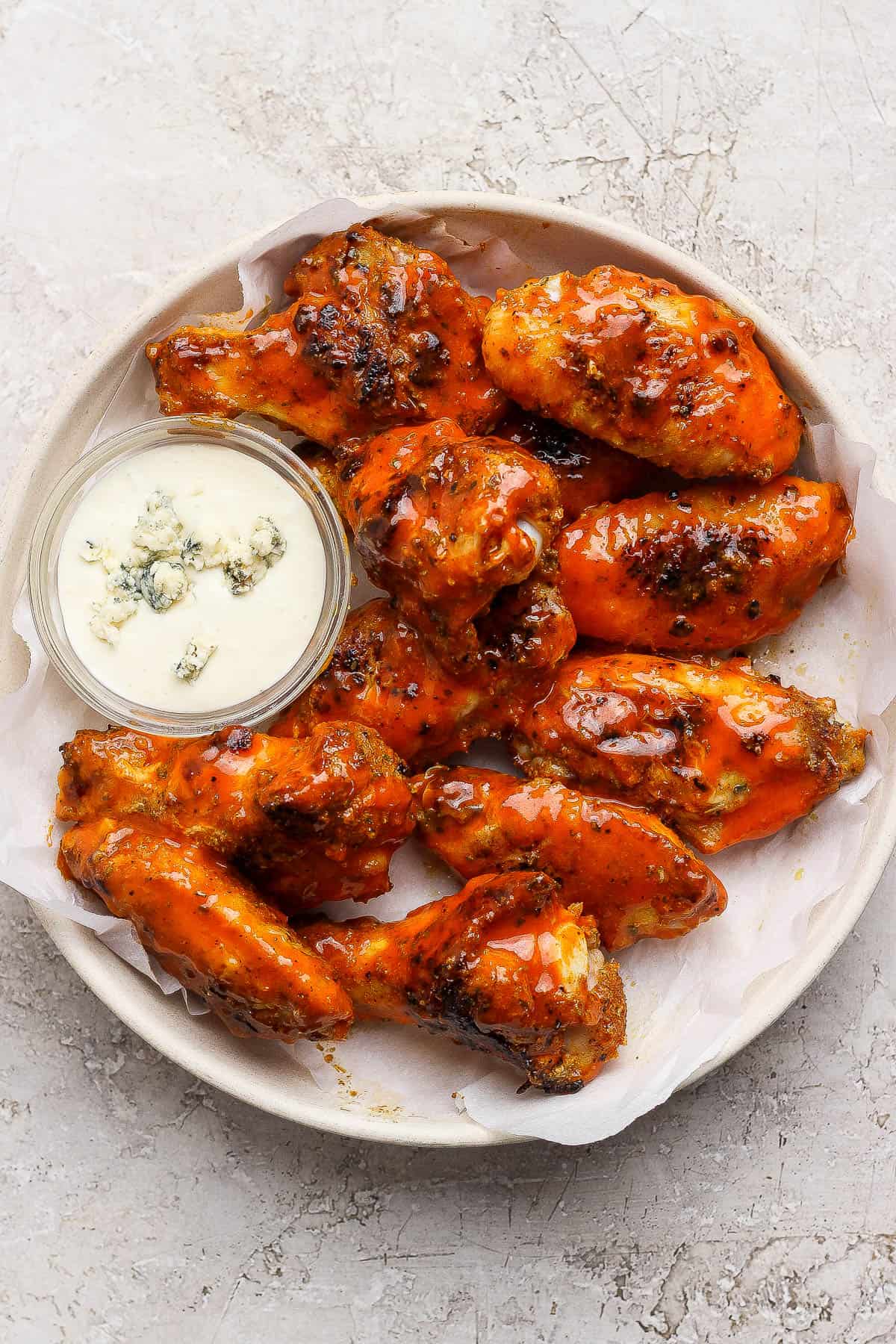 Buffalo Blackstone chicken wings in a bowl with a dish of blue cheese dressing.