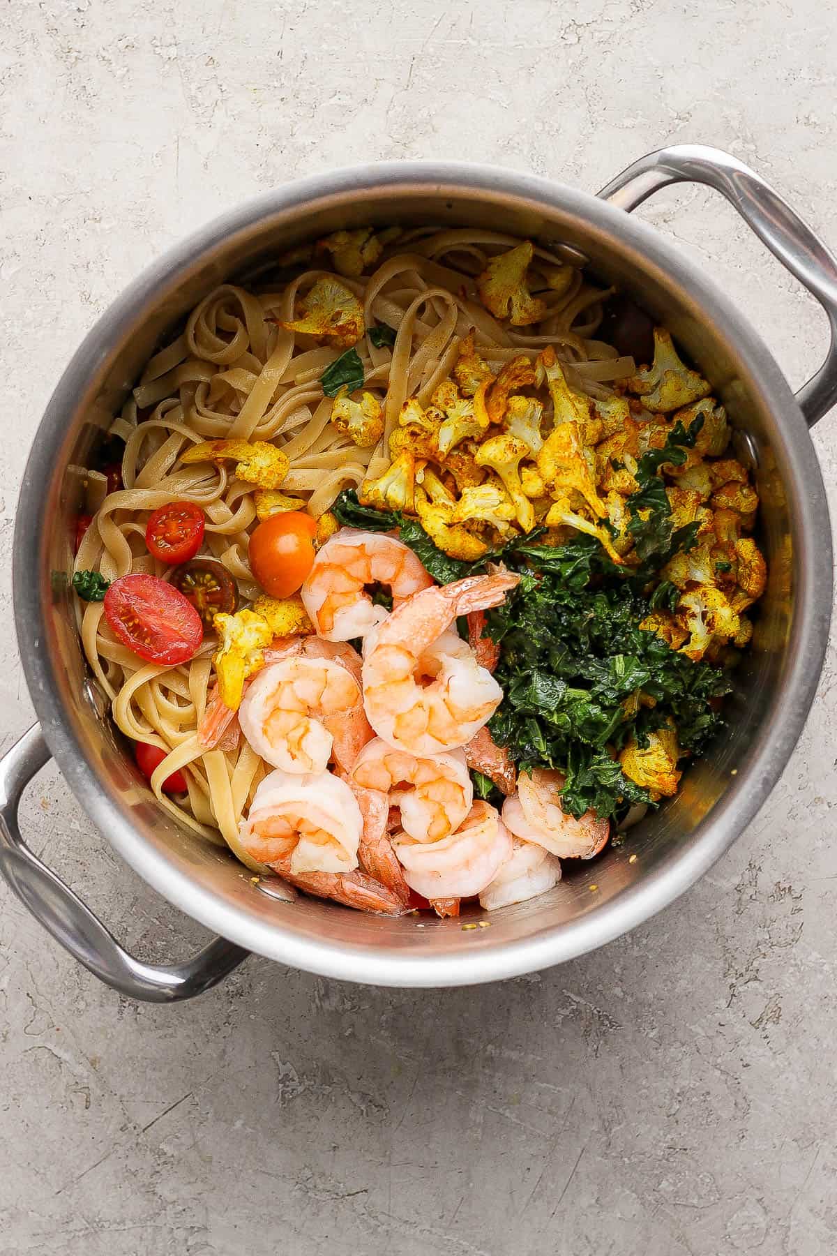 Turmeric pasta with shrimp and cauliflower in a large metal pot before the final mix.