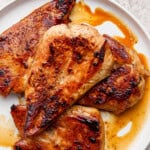 Fully cooked and juicy Blackstone chicken breasts resting on a white plate.