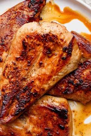 Fully cooked and juicy Blackstone chicken breasts resting on a white plate.
