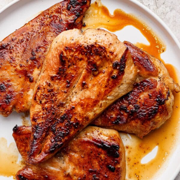Fully cooked and juicy Blackstone chicken breasts resting on a white plate.