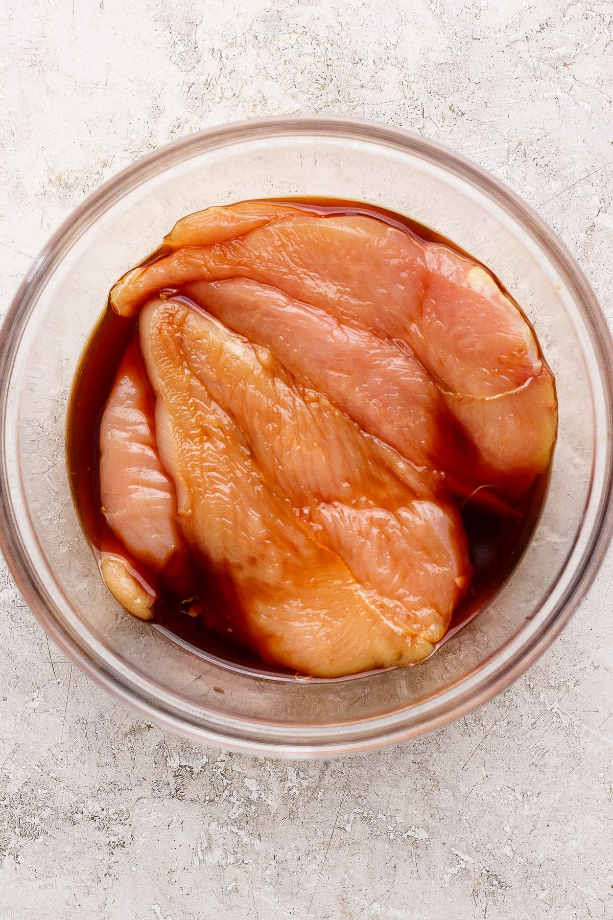 Chicken cutlets marinating in soy sauce before being cooked on the Blackstone griddle.
