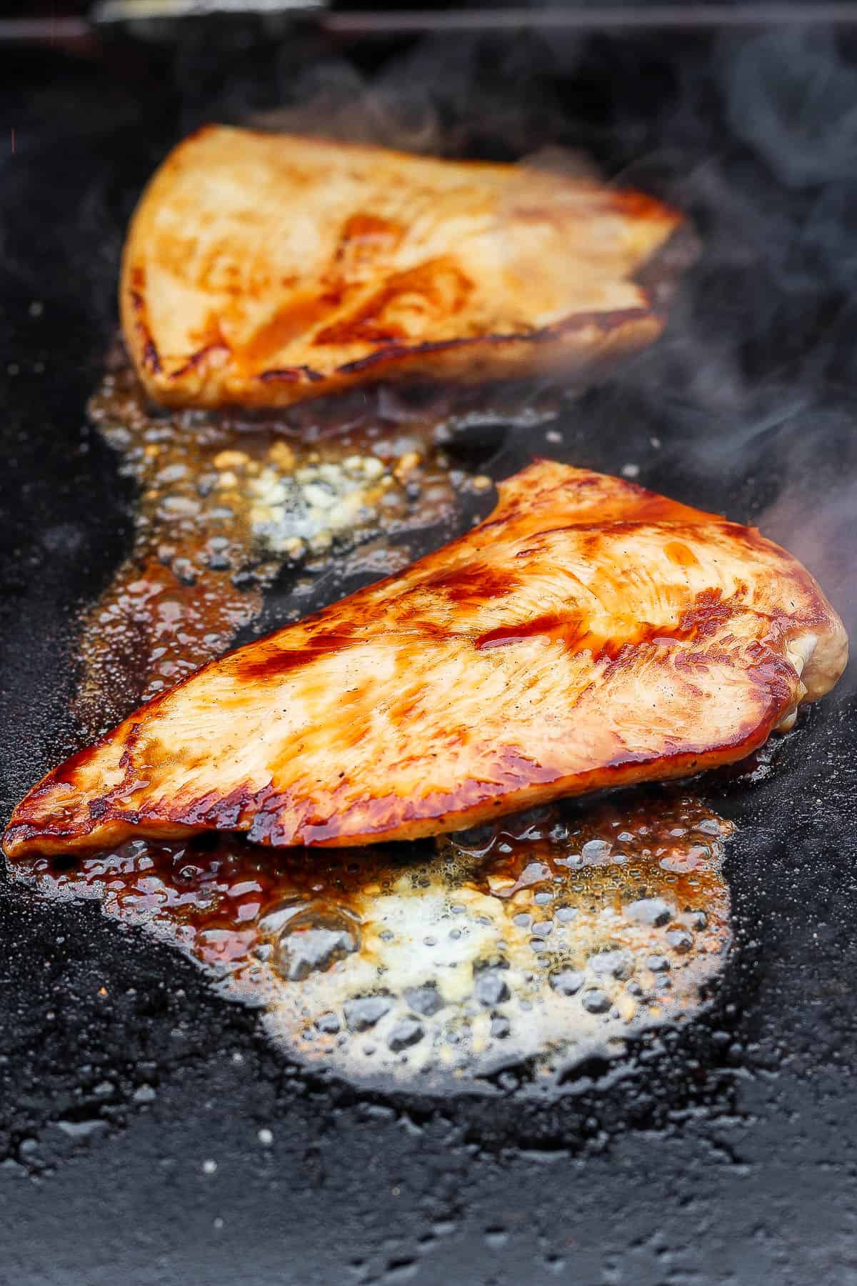 Chicken breasts on the Blackstone fully cooked with a drizzle of soy sauce and some melted garlic butter.