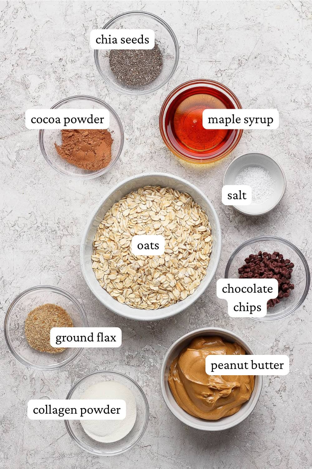 Ingredients for chocolate peanut butter energy balls in separate bowls with labels.