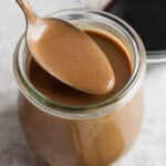 A jar of homemade creamy balsamic dressing with a spoon lifting some out.