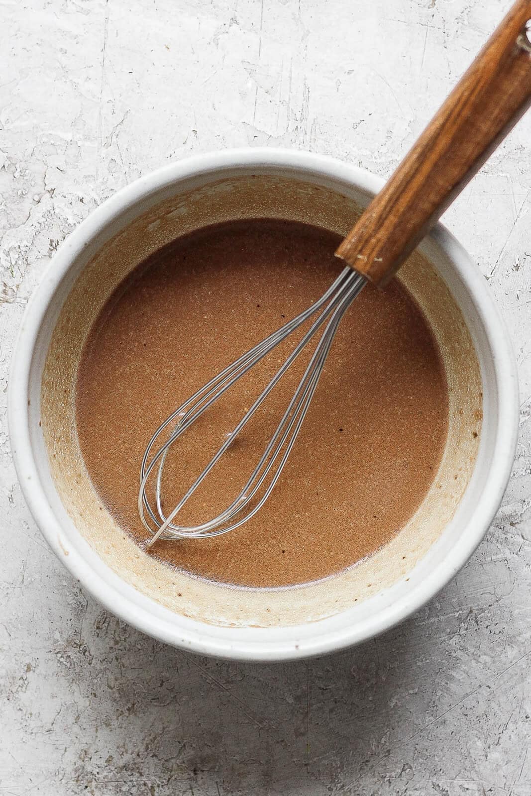 Ingredients mixed in a bowl with a small whisk sticking out. 