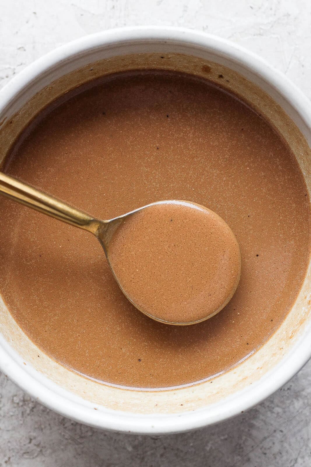 A bowl of creamy balsamic dressing with a spoon lifting some out.