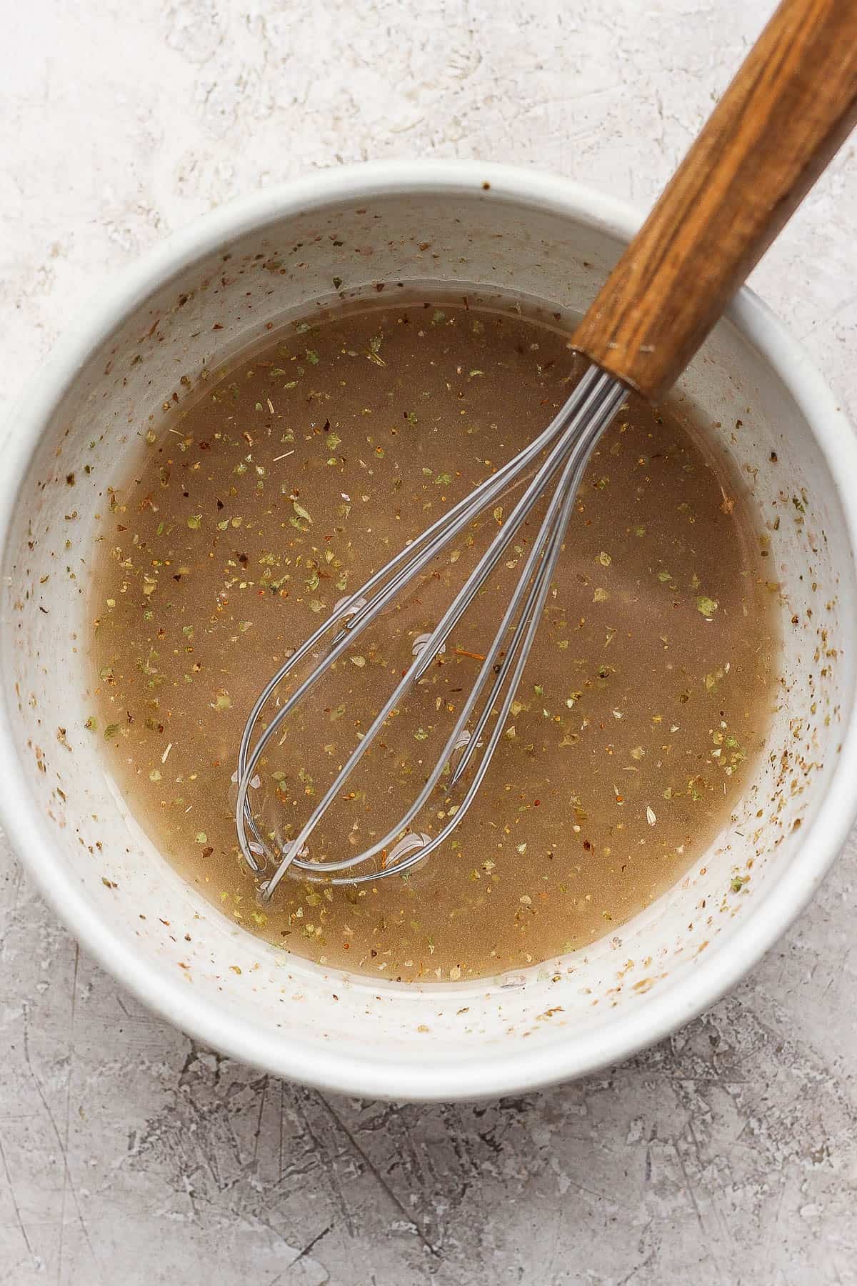 Greek vinaigrette in a small bowl after being fully mixed with a whisk.
