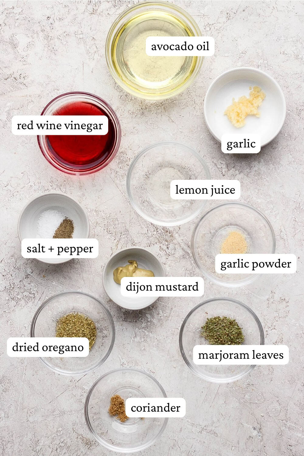 Ingredients for Greek vinaigrette in small bowls with labels.