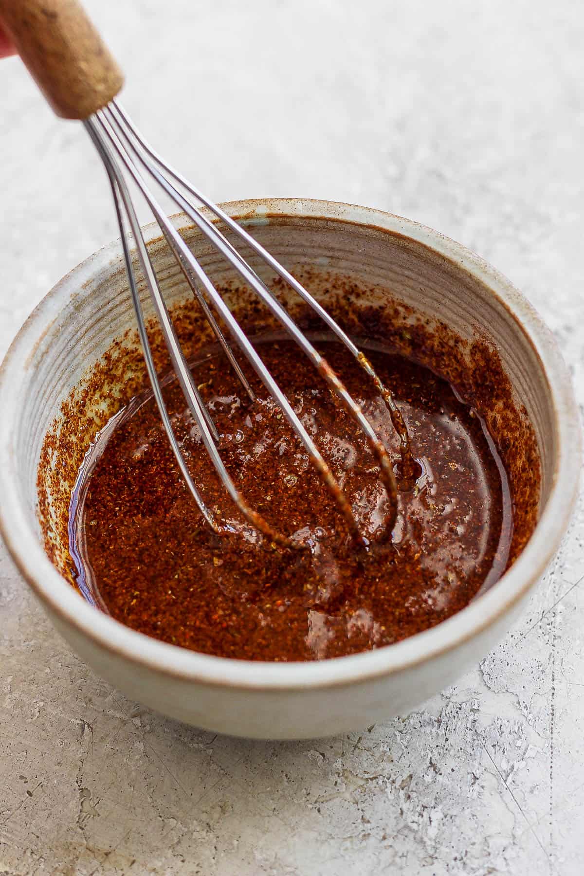 The marinade for grilled chicken fajitas in a small bowl with a whisk.